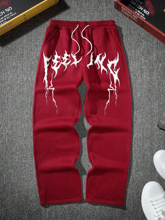 Red sweatpants with white graphic design on a gray surface